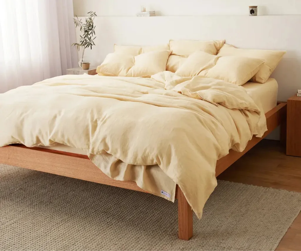 butter yellow best linen sheets with multiple pillows on wooden bedframe