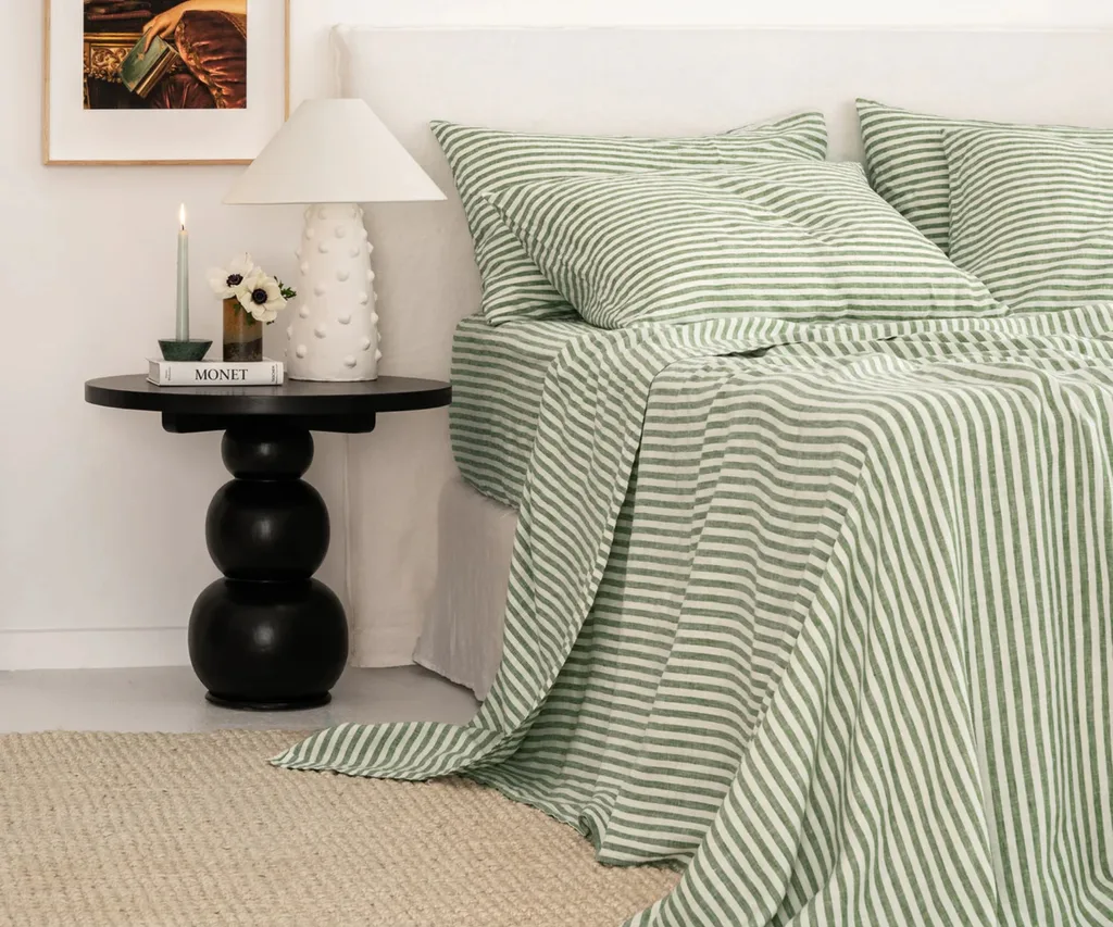 best linen sheets made from white and green stripe fabric draping over side of bed