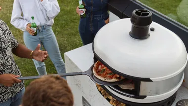 people gathered around a dome pizza oven