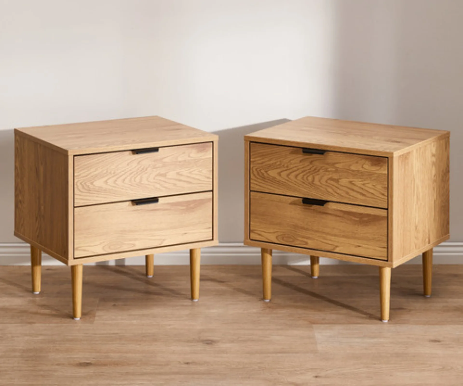 two bedside tables facing each other made of light coloured wood with two drawers