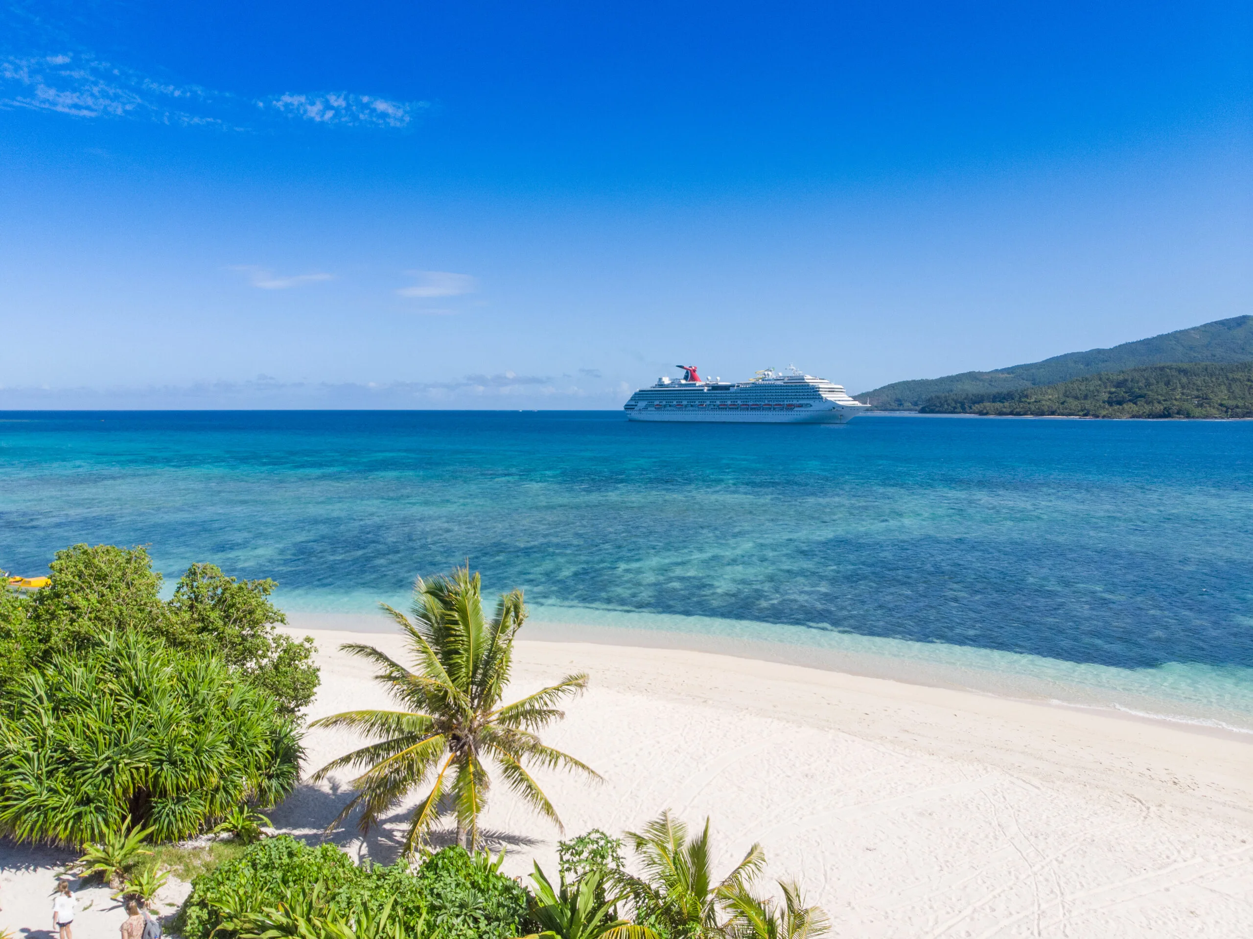 Carnival Splendor cruise ship off a tropical island in blue water