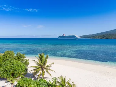 Carnival Splendor cruise ship off a tropical island in blue water