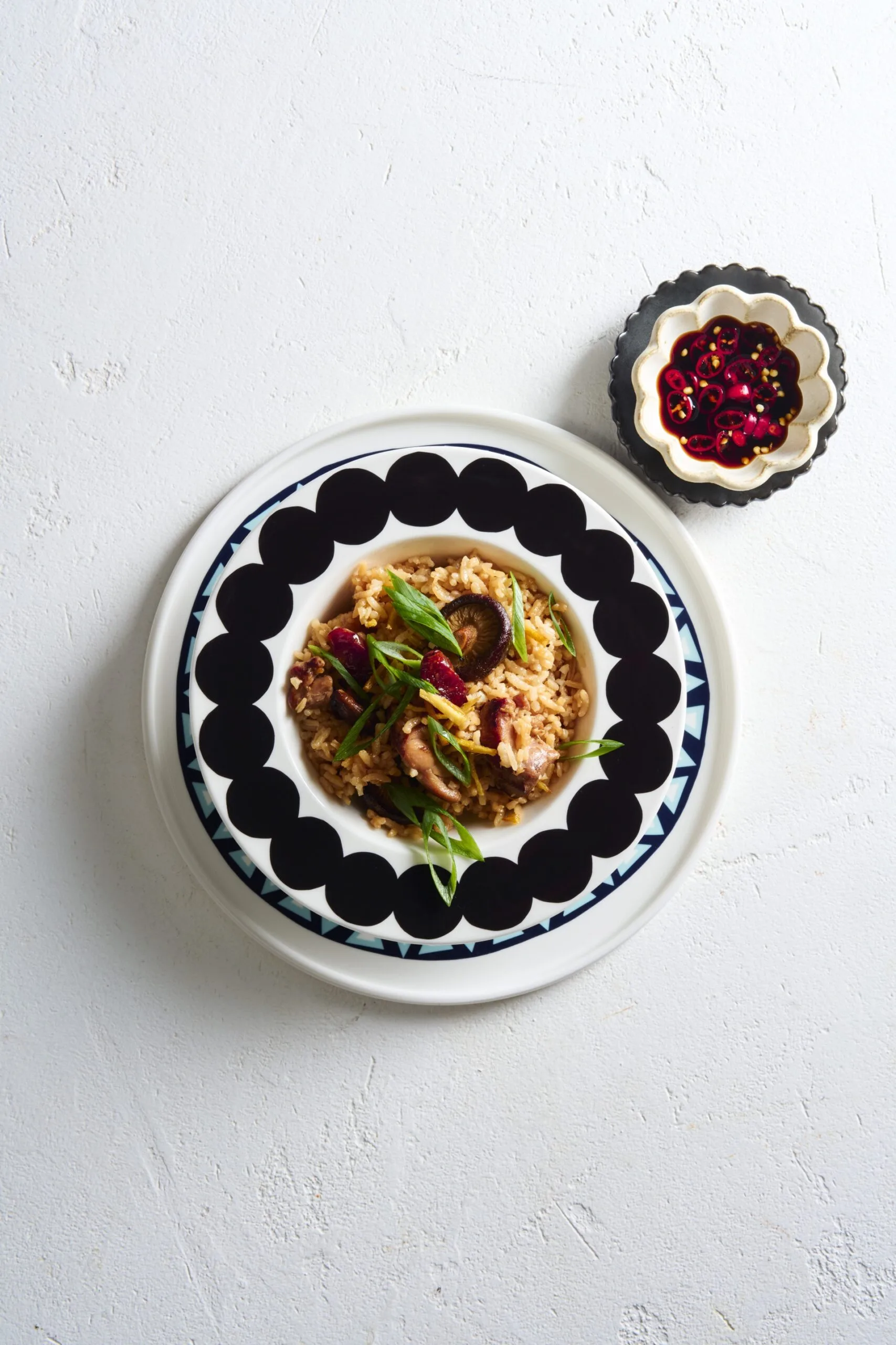 clarissa's claypot chicken rice in patterned bowl with small bowl of chili on the side