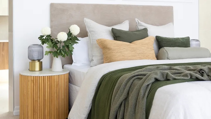 bedroom with white sheets and deep green throw blanket