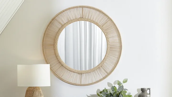 A rattan mirror, like this Cora round design from Temple & Webster, can add laid back and chic style to your home.