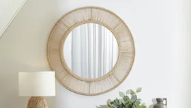A rattan mirror, like this Cora round design from Temple & Webster, can add laid back and chic style to your home.
