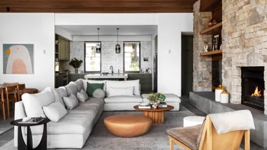 Lounge room with walnut roof and stone fireplace and kitchen