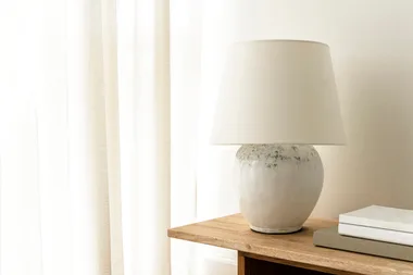 white table lamp with dark pigments on a wooden table with books beside it