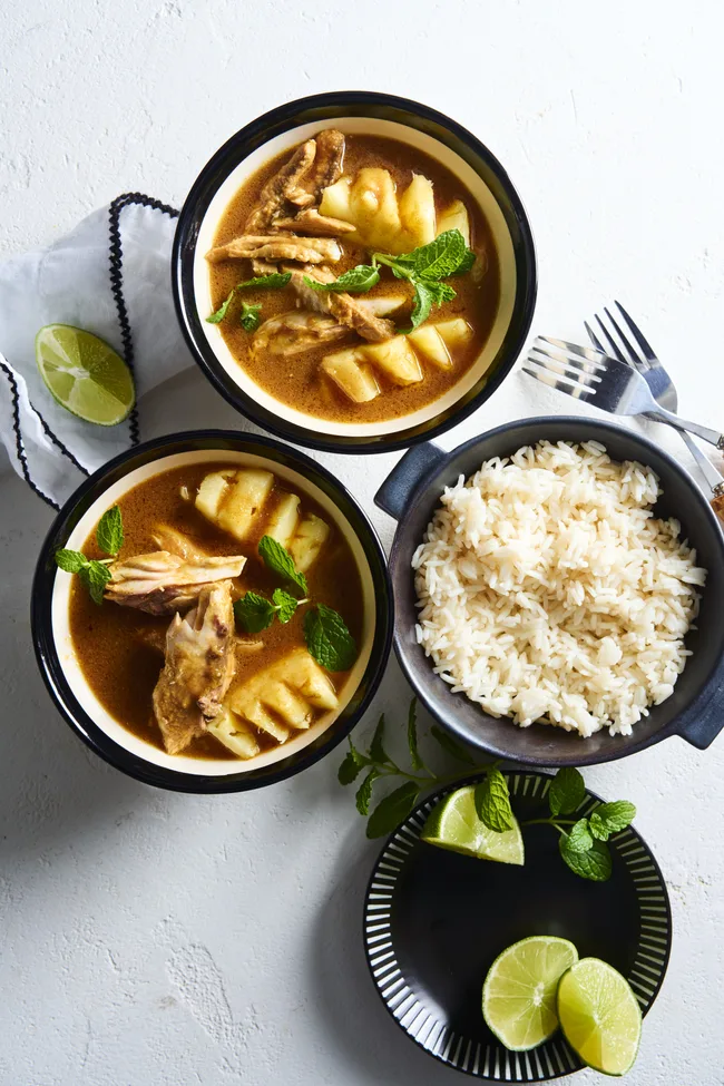 tamarind fish curry in two bowls with bowl of rice on the side