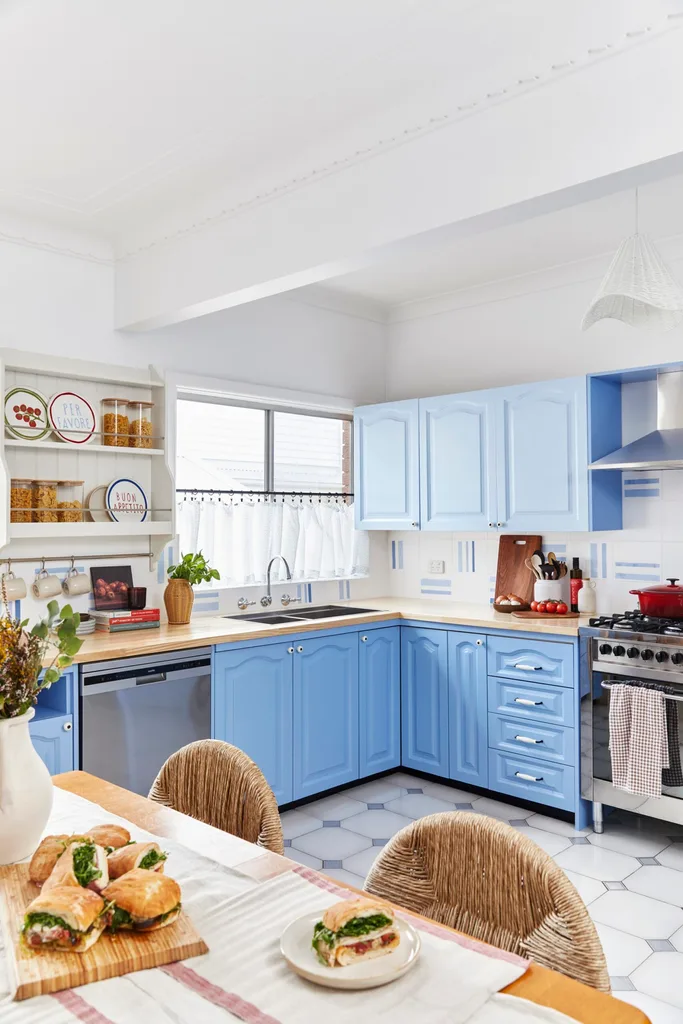 blue painted kitchen with table in foreground and diagonal shot of kitchen cupboards