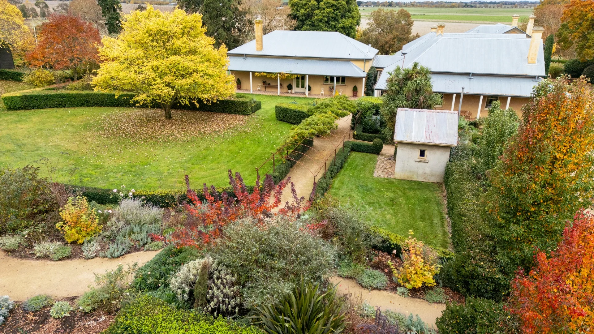 birds eye view of the ceres homestead with formal hedging around the gardens, lawn space and pops of colour from purple, orange and yellow foliage