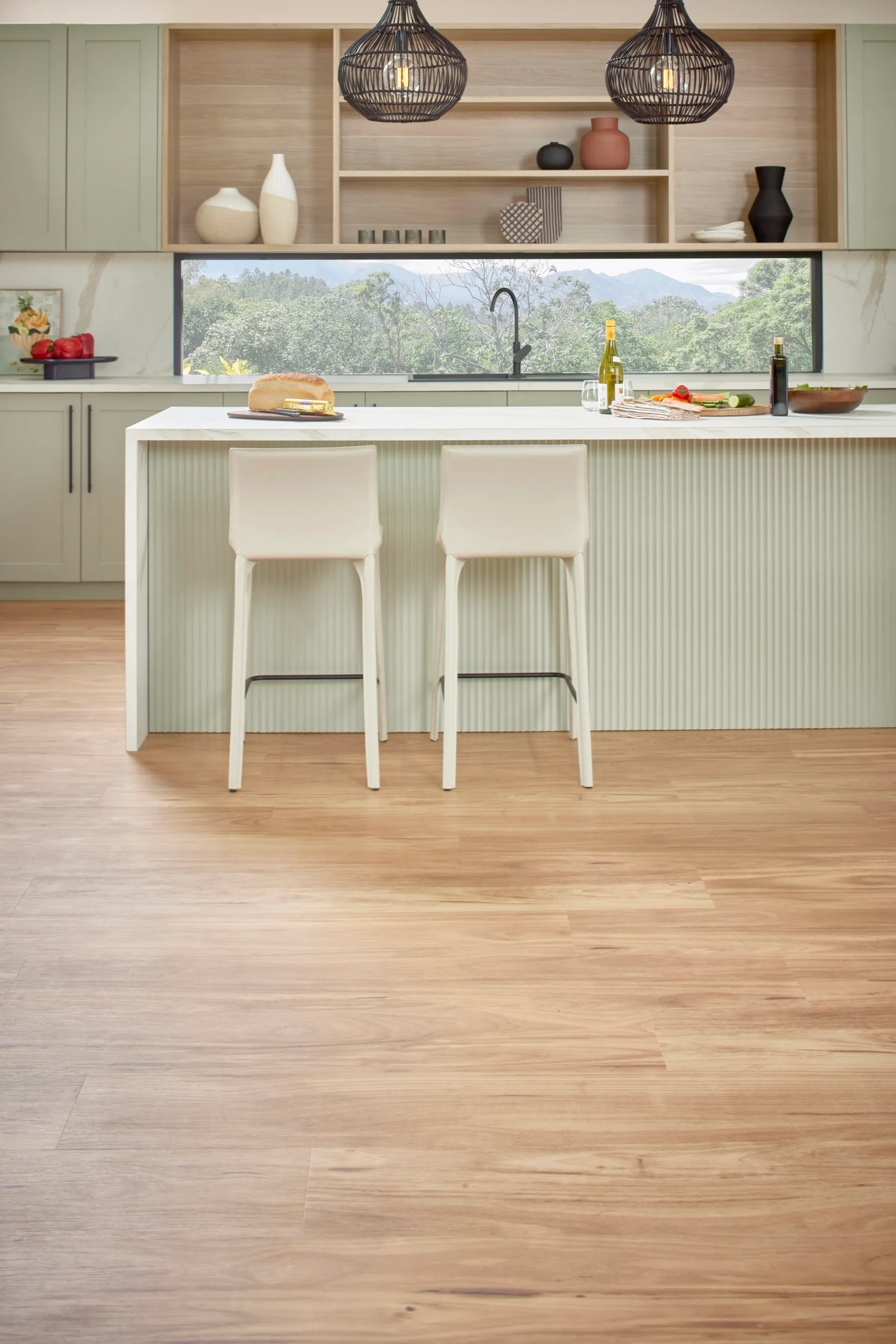 modern kitchen with green cupboards and light coloured engineered flooring