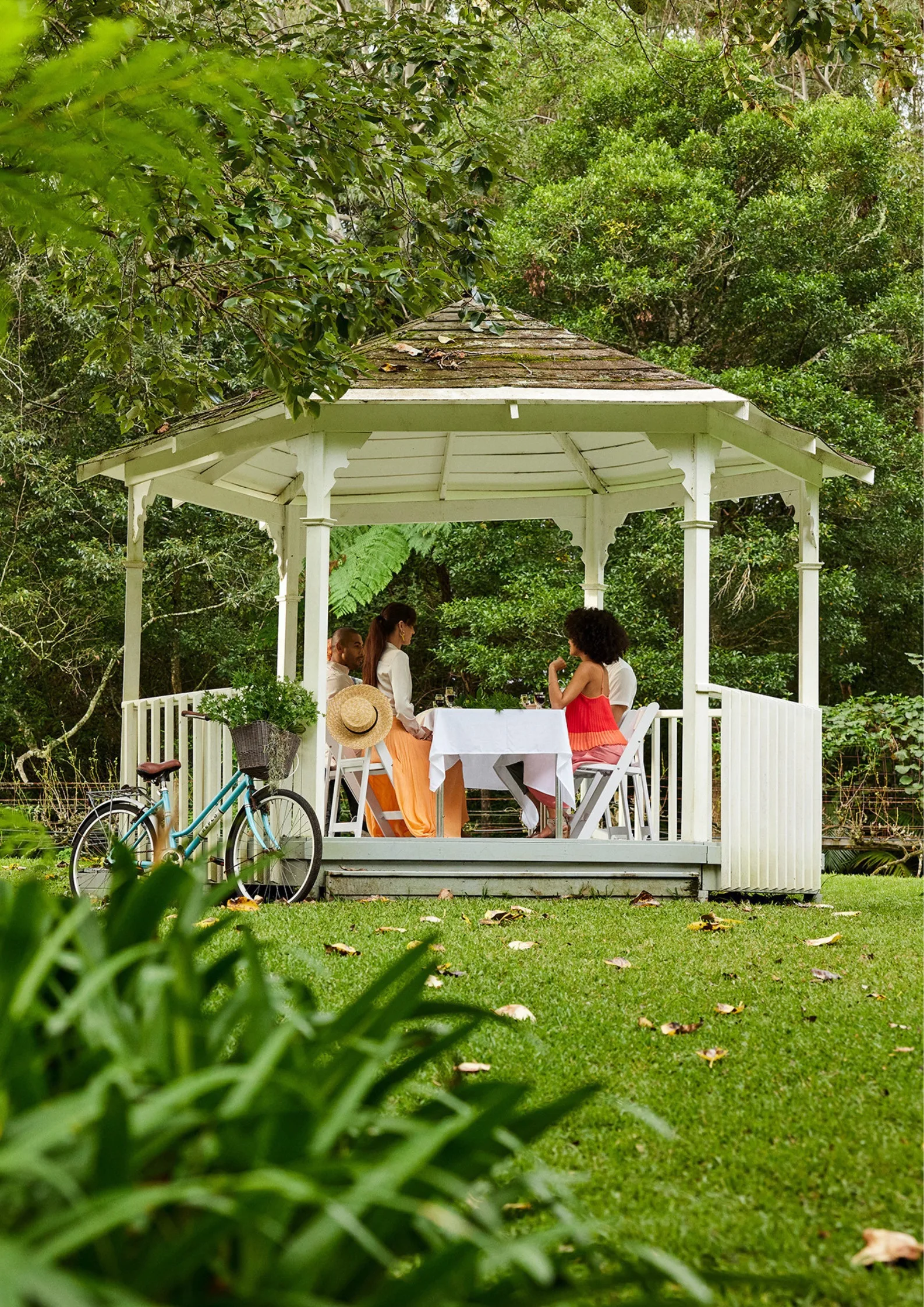 guests sitting in gazebo with orange skirt and red dress bike in the corner of the shot