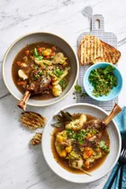 irish stew in two bowls with parsley on the side