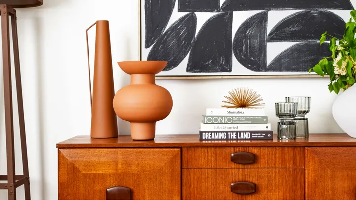 Mid century style buffet console styled with terracotta vases, sunburst ornament and coffee table books.