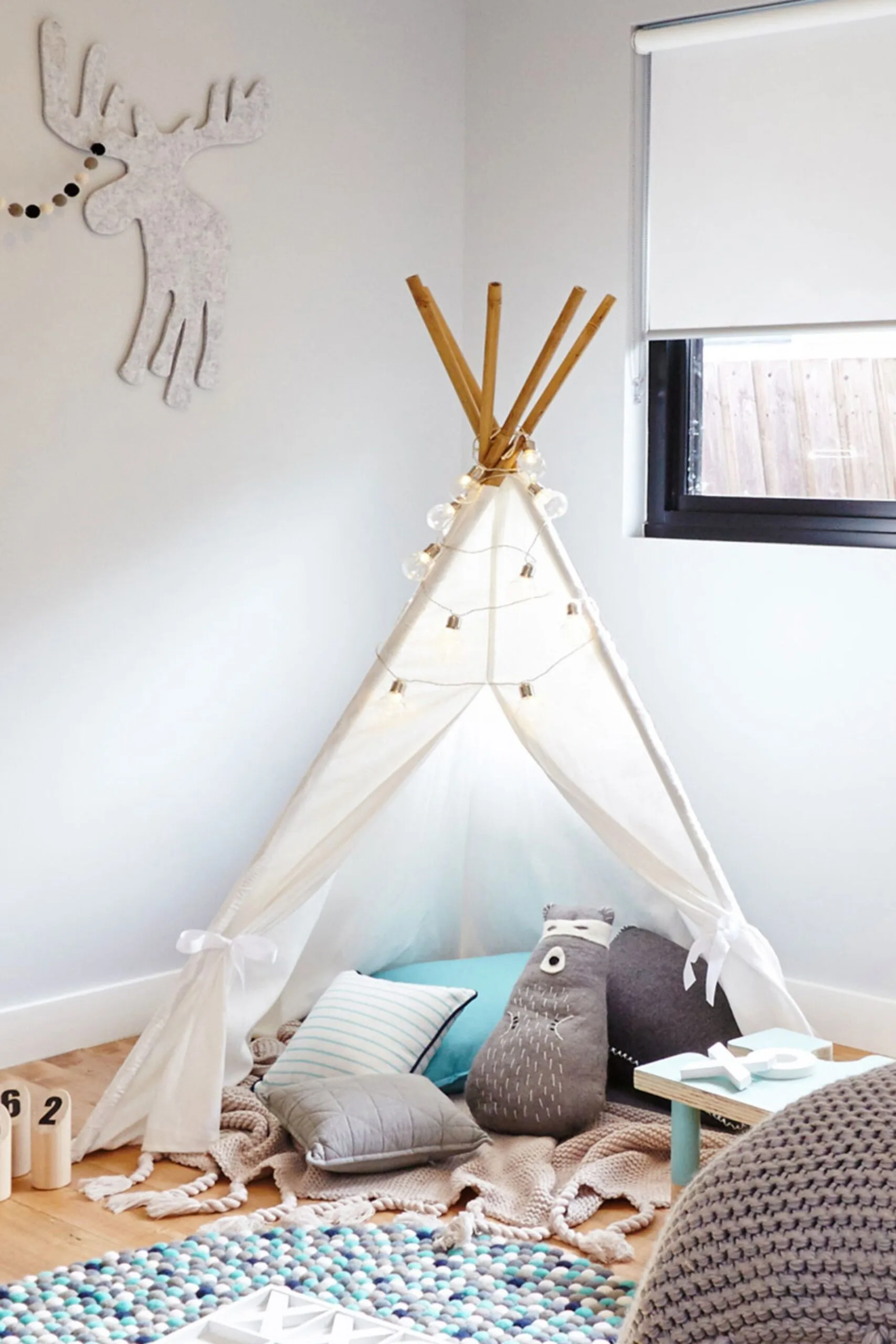 teepee with cushions underneath made of wooden dowels and fabric
