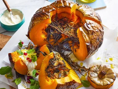 whole baked pumpkin cut open with pomegranate and goats cheese