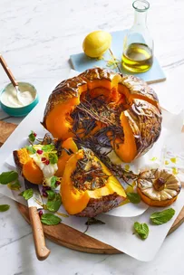 whole baked pumpkin cut open with pomegranate and goats cheese