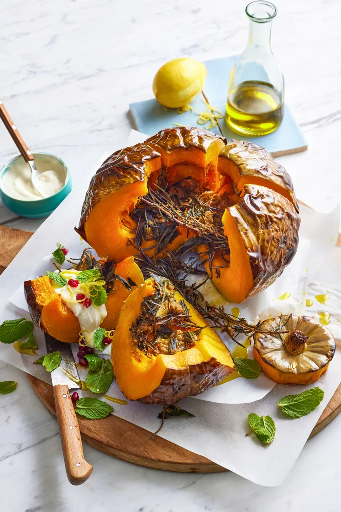 whole baked pumpkin cut open with pomegranate and goats cheese