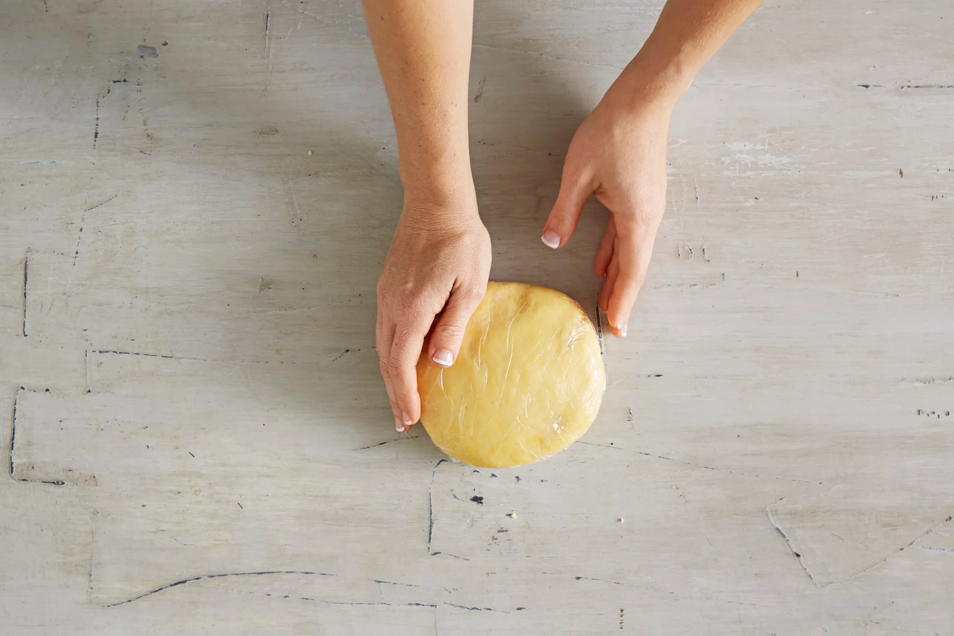 hands holding a circle mound of shortcrust pastry