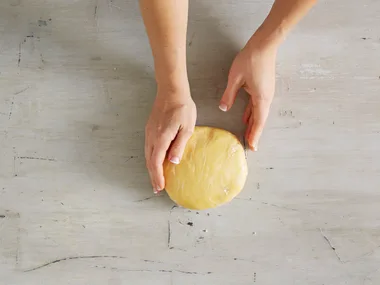 hands holding a circle mound of shortcrust pastry