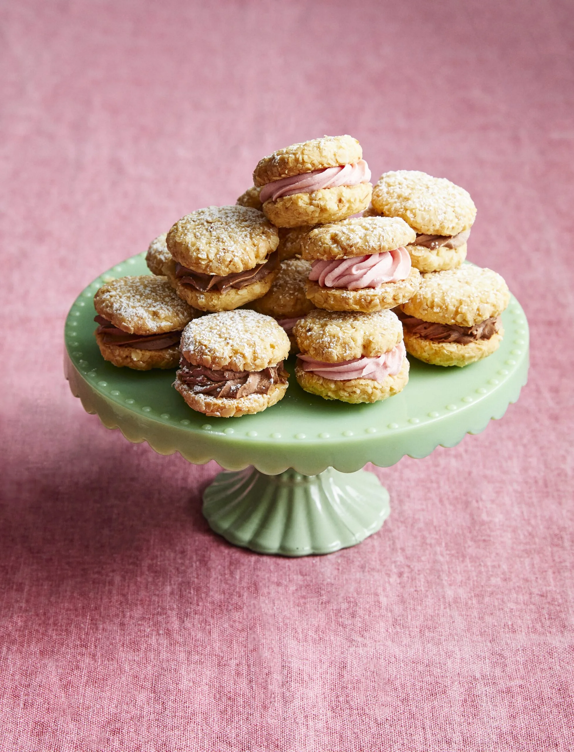 melting moments on a green cupcake stand stacked up, with berry and chocolate filling alternating each biscuit