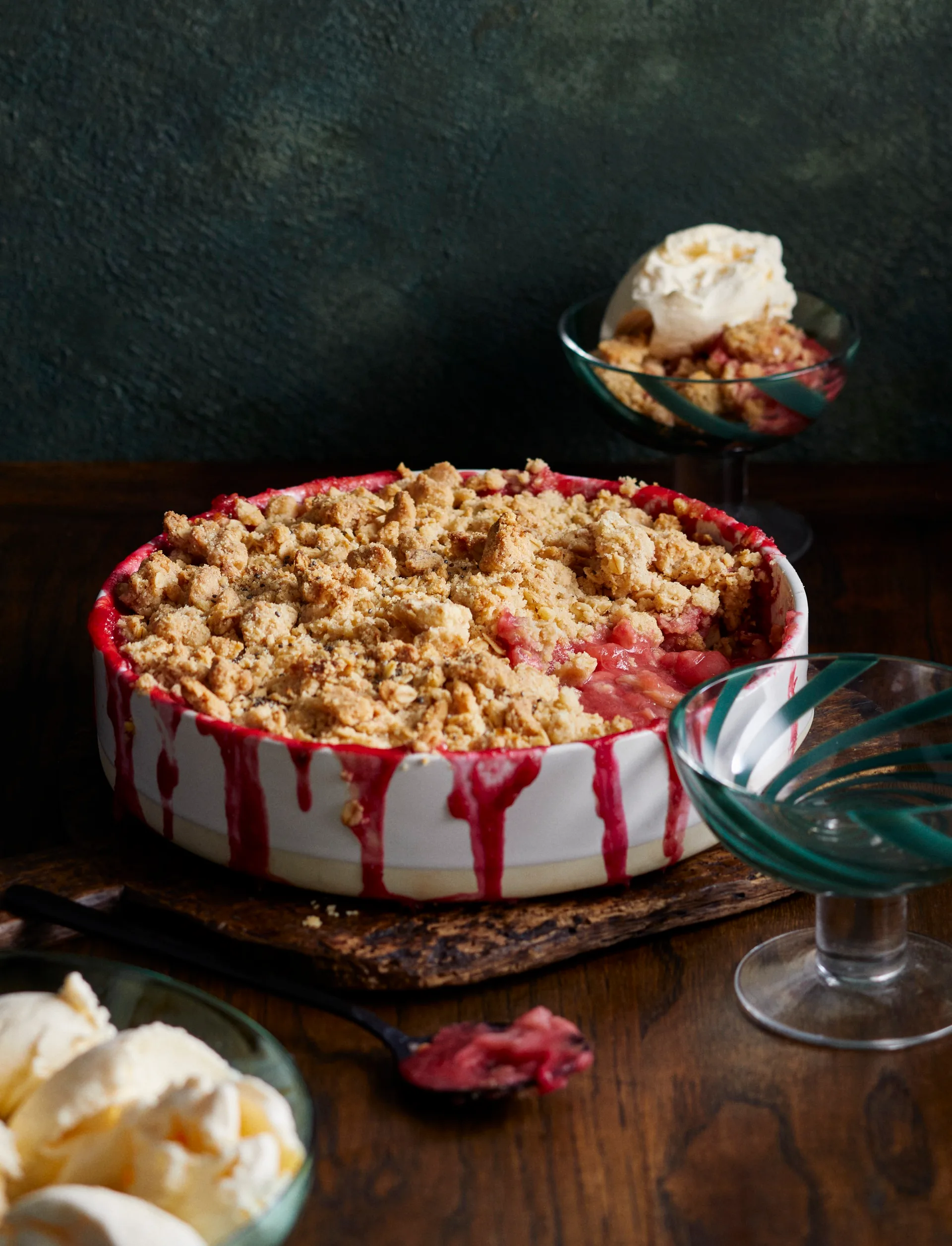 apple and rhubarb crumble in circle white pie dish with red dripping down the edges