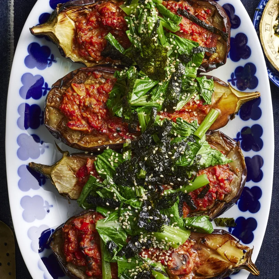picture of four slices of eggplant cooked with miso sauce and asian greens on top. One blue plate with flowers around the edge