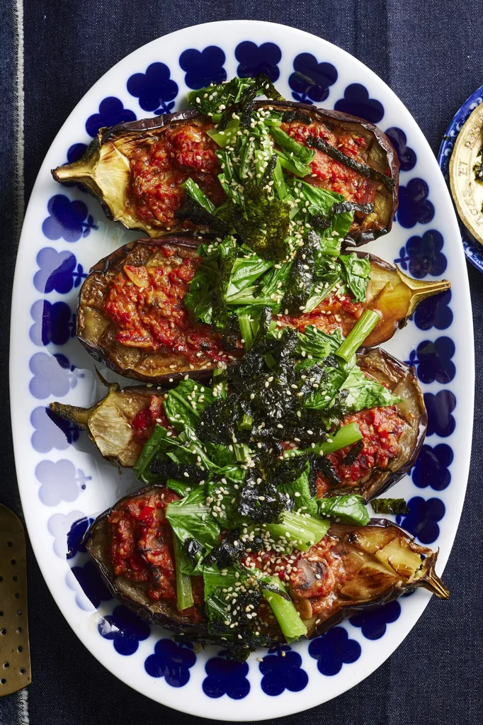 picture of four slices of eggplant cooked with miso sauce and asian greens on top. One blue plate with flowers around the edge