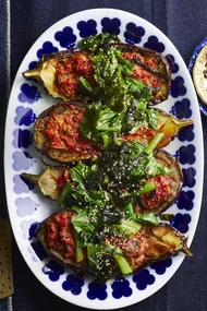 picture of four slices of eggplant cooked with miso sauce and asian greens on top. One blue plate with flowers around the edge