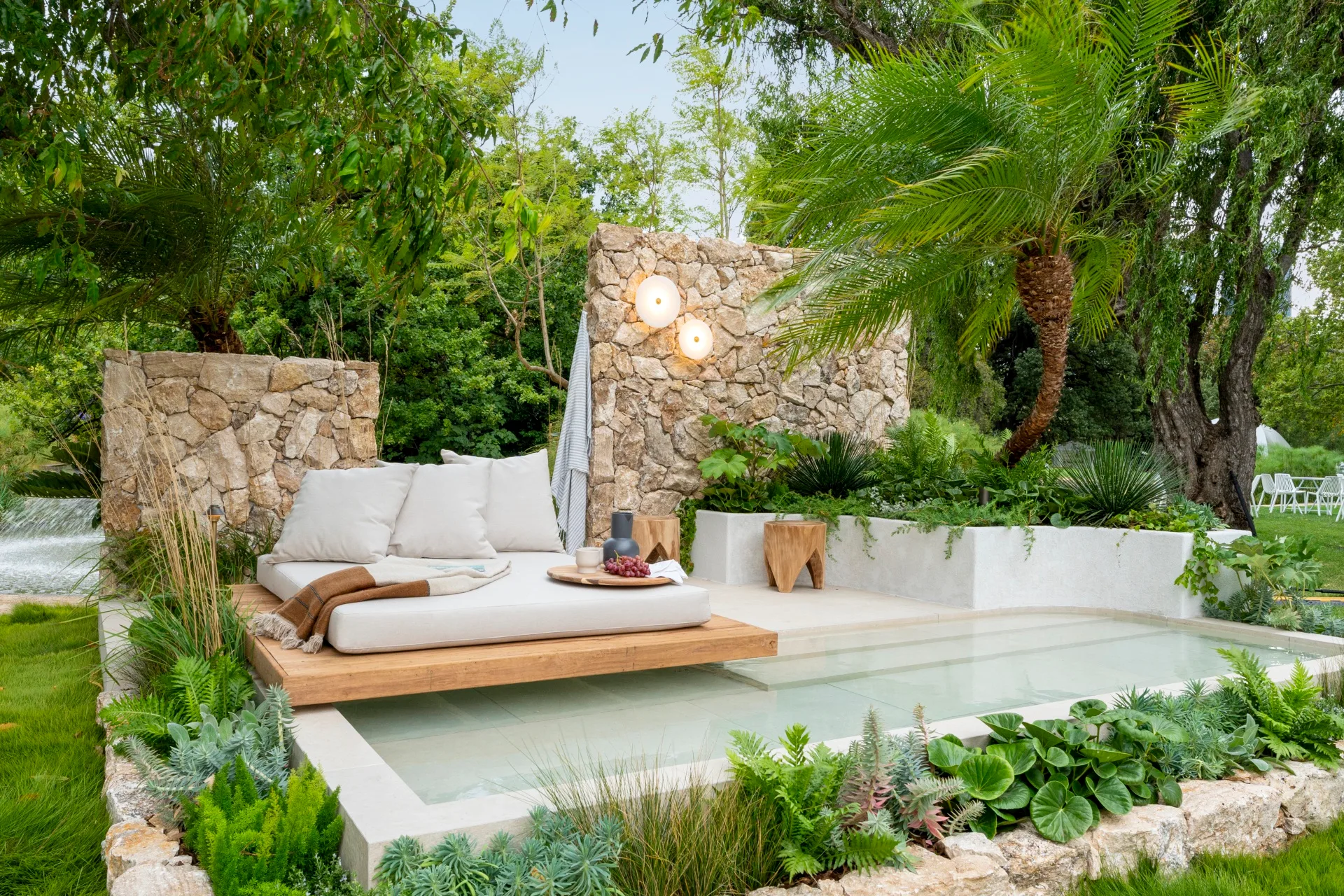 garden design style in a sanctuary with raised floating day bed over pool and ferns and palms surrounding the space