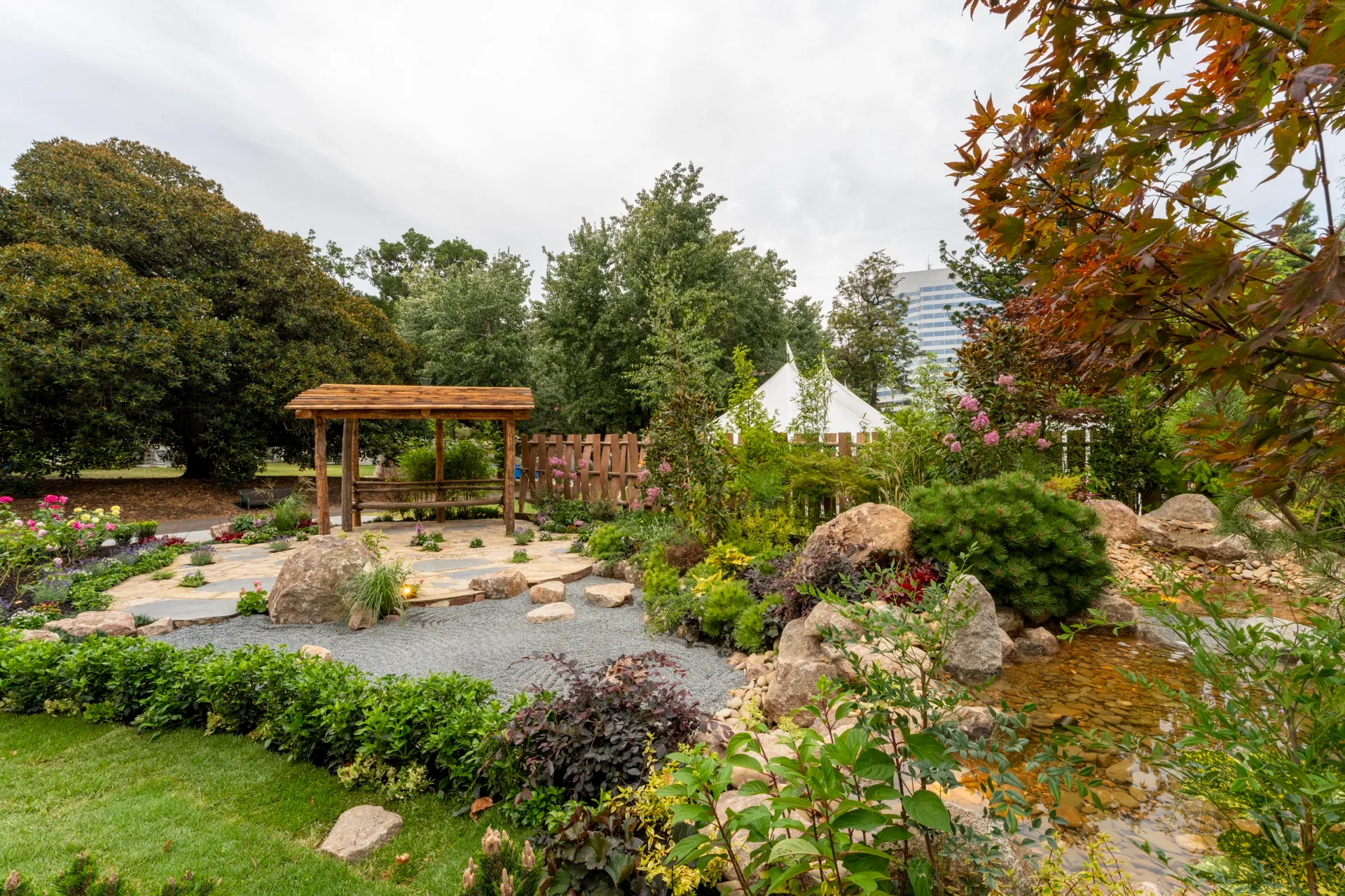 japanese garden design style with raked stone flooring, a wooden pavilion and lots of boulders amongst the plants