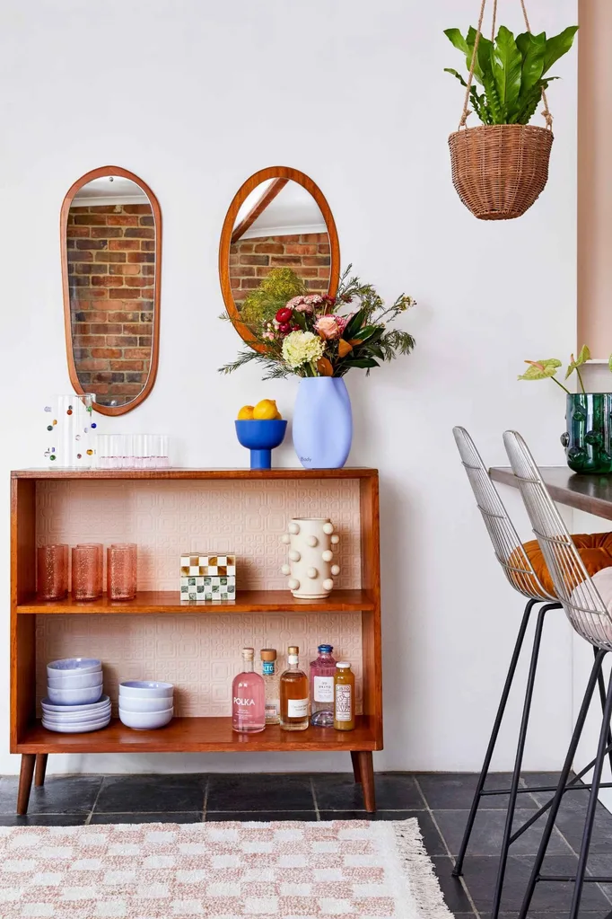DIY shelf with mirrors hung above it on the wall and a checker rug