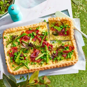 close up birds eye view of quiche decorated with asparagus and prosciutto on top