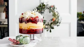 Kitchen bench with a Christmas trifle and decorative green baubles on it. A Christmas wreath is visible in the background.