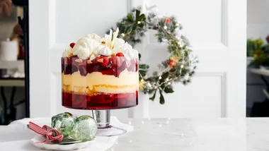 Kitchen bench with a Christmas trifle and decorative green baubles on it. A Christmas wreath is visible in the background.