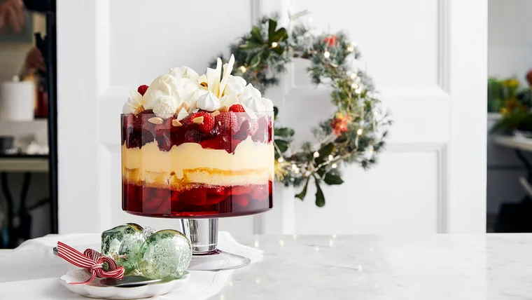 Kitchen bench with a Christmas trifle and decorative green baubles on it. A Christmas wreath is visible in the background.