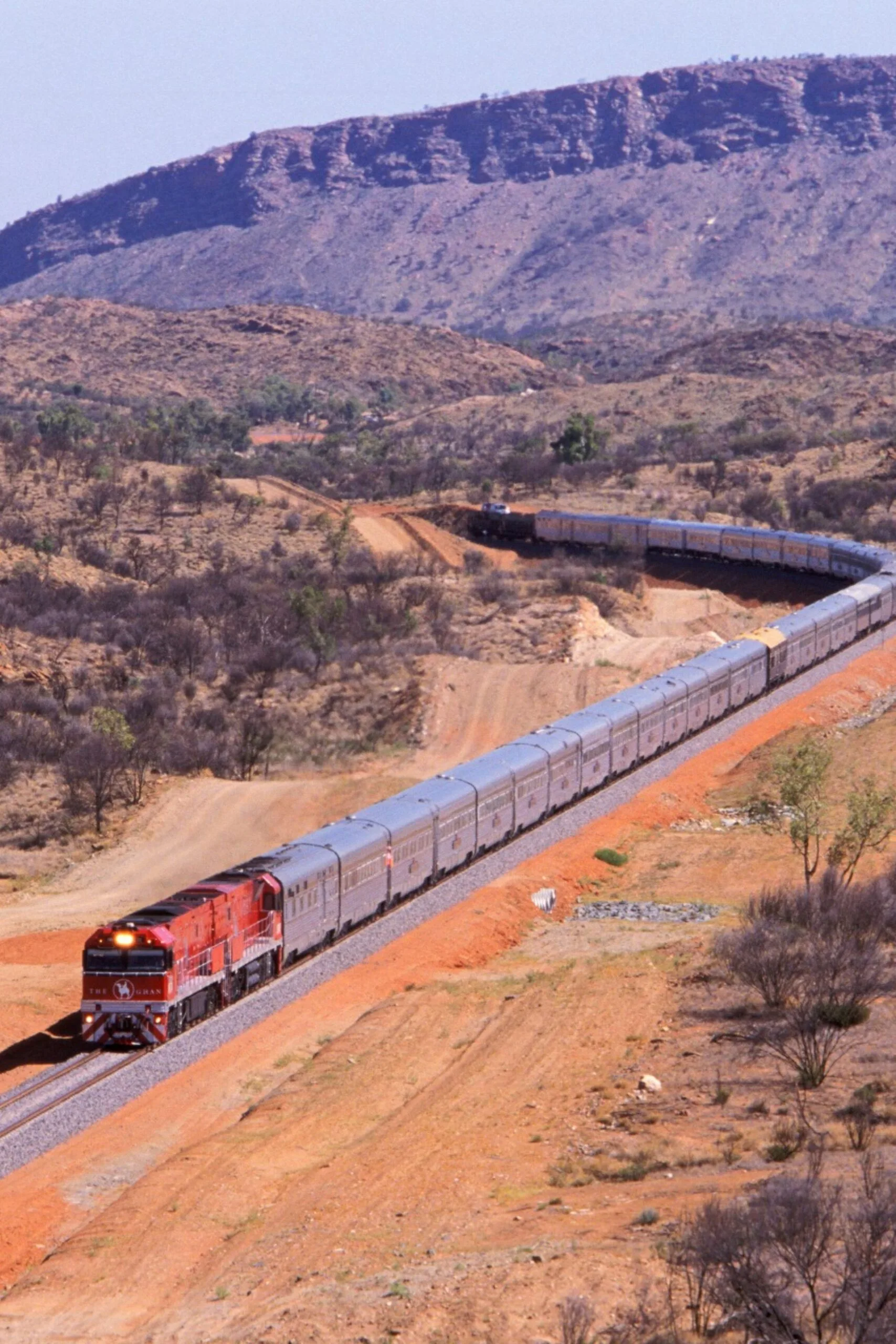 the ghan train with red sand and rolling hills