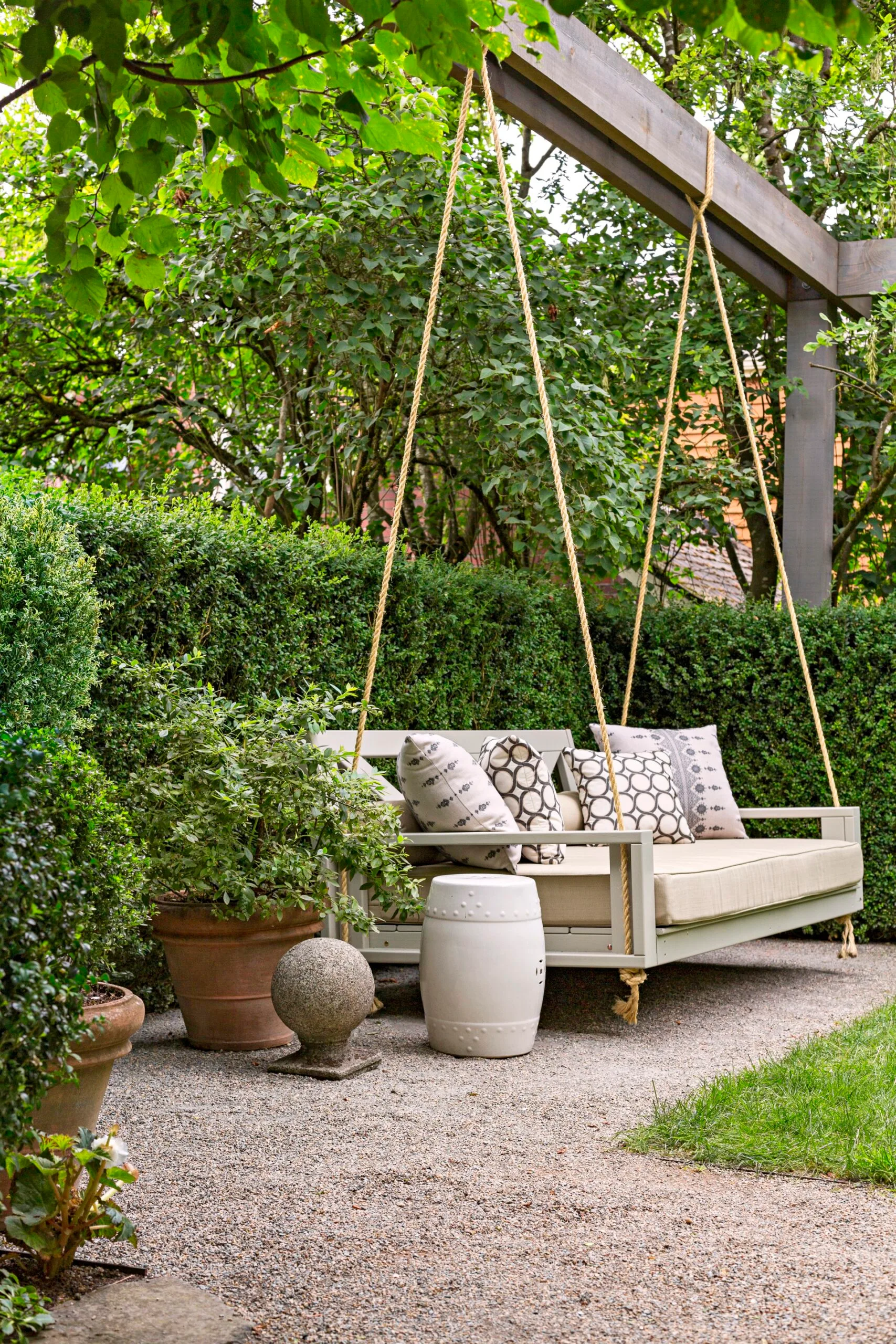 porch swing seat on large wooden frame with short hedge behind it