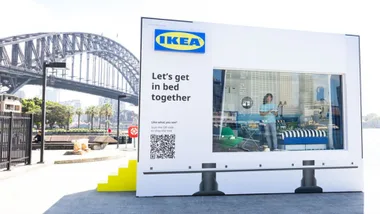 IKEA billboard box with bedroom inside and harbour bridge behind it