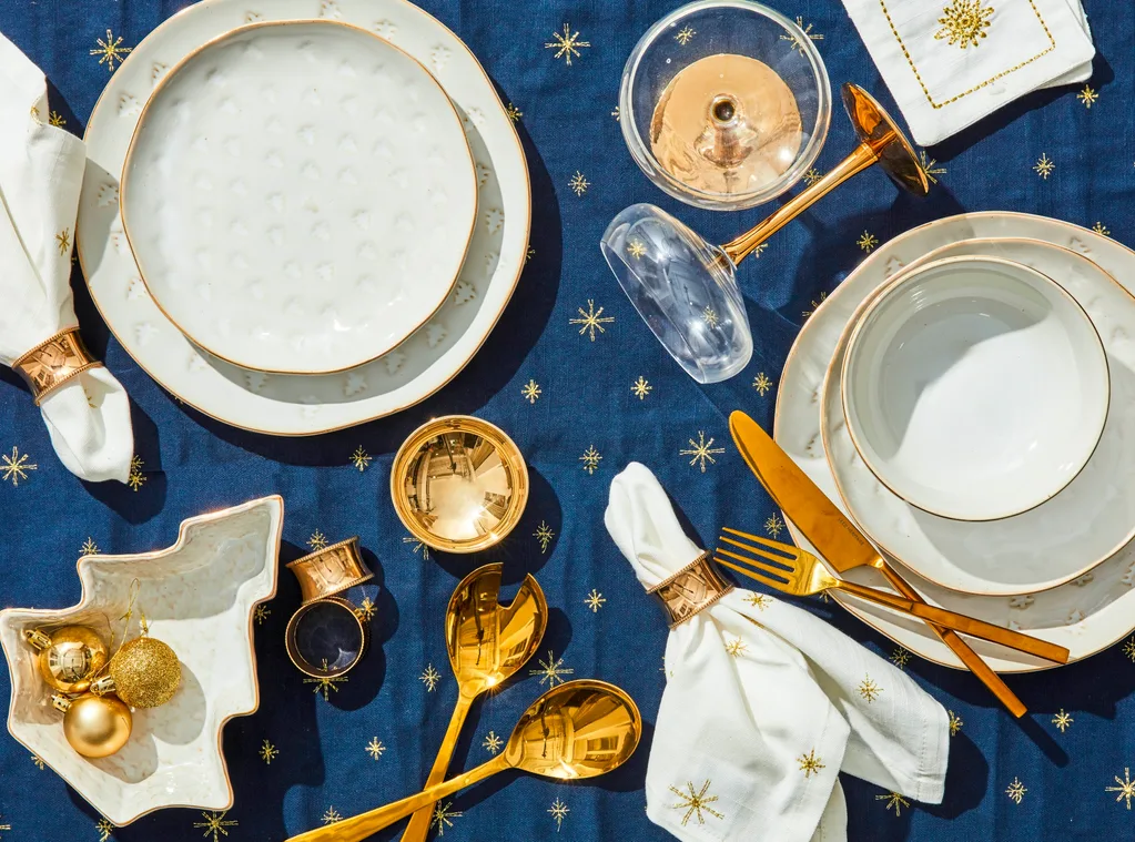 starry christmas table theme with gold rimmed crockerts gold cutlery adn embroided stars on linens
