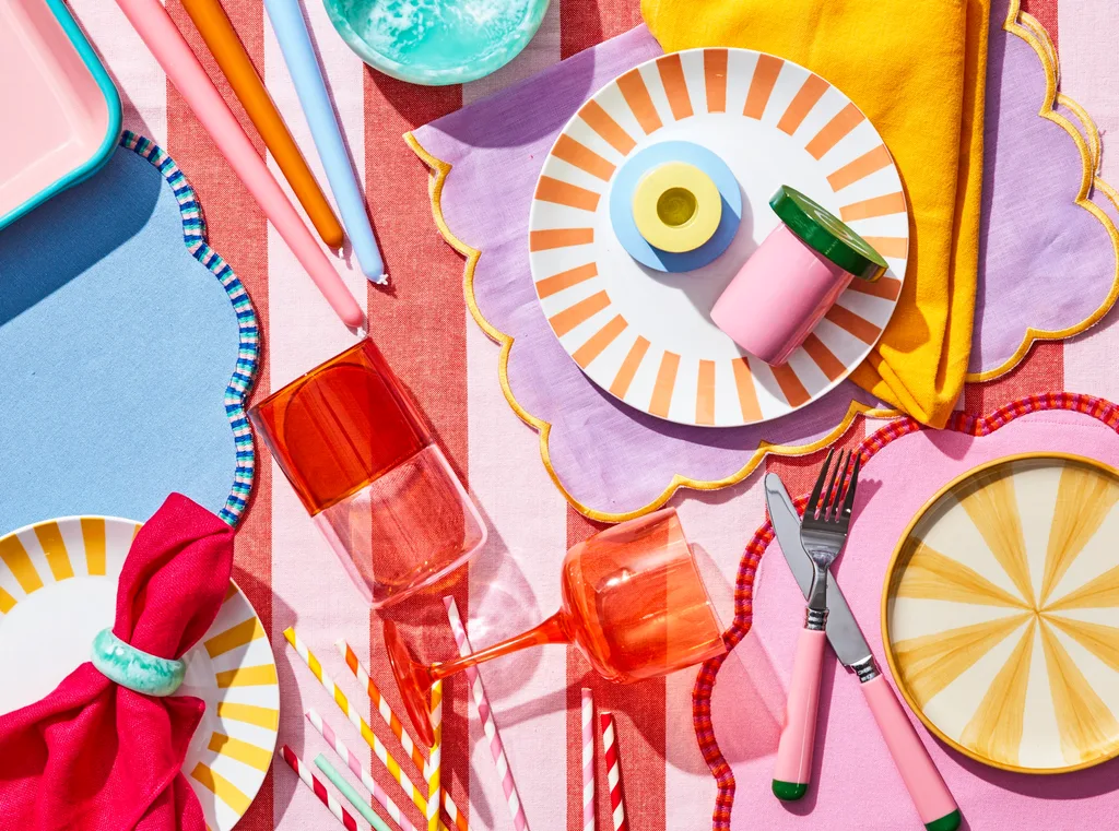 christmas table theme of maximalism with stripy plates pink, purple and yellow candles and colourful tablecloths