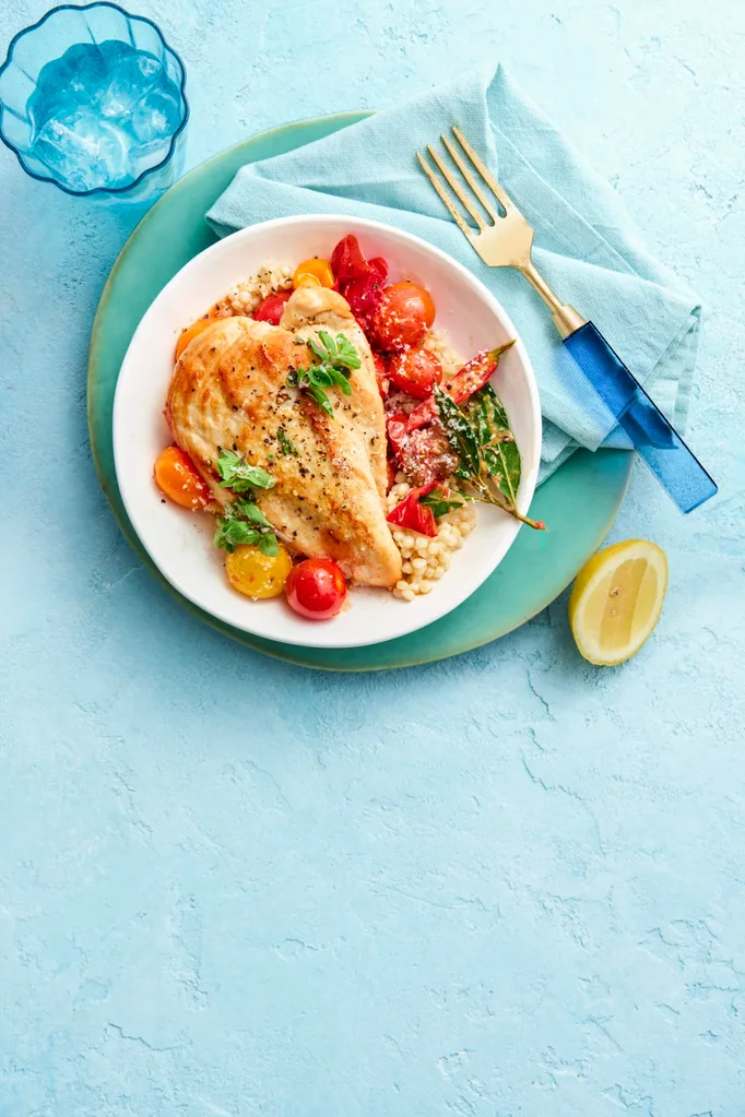 pan fried chicken in bowl with couscous vegetables against a blue background