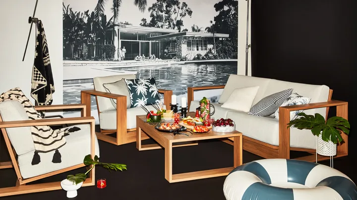 Modern living area with wooden furniture, a pool mural, and a coffee table with assorted snacks and drinks.