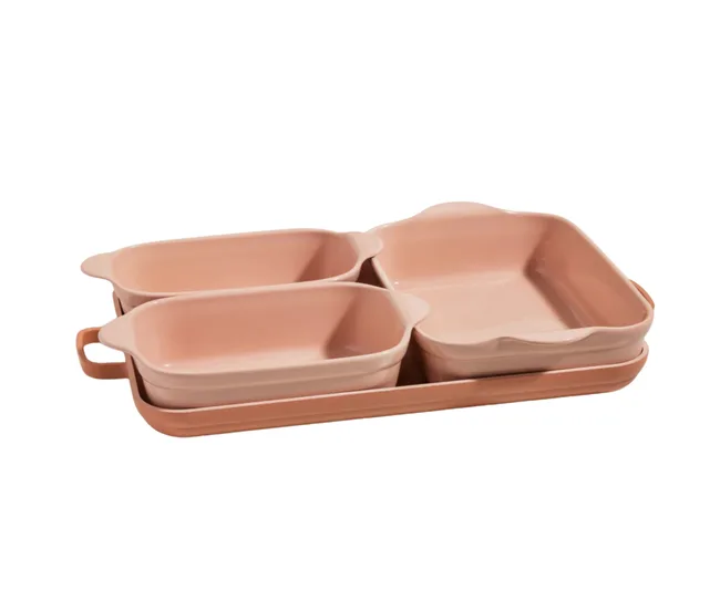 Set of four pink ceramic baking dishes in various shapes and sizes neatly stacked together.