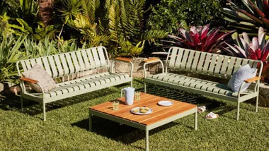 image of two sage green metal lounge seater chairs with wooden table top coffee table in the middle