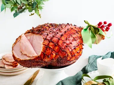 chirstmas ham with green ribbon on the end and garland in the background