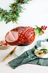 chirstmas ham with green ribbon on the end and garland in the background