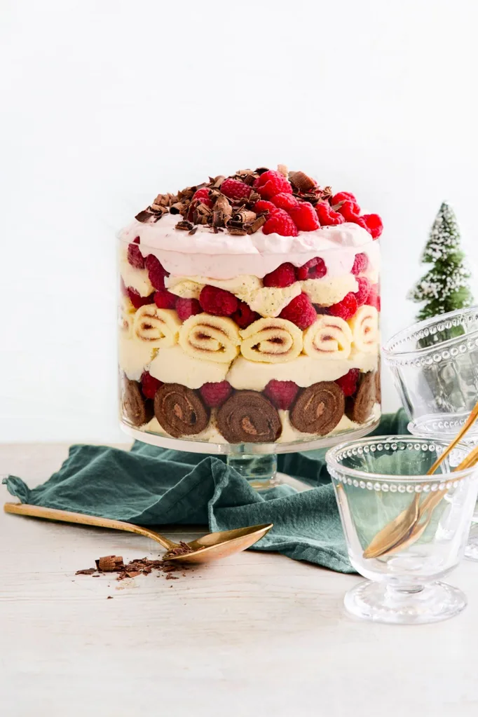 trifle with layers of panna cotta and jam scroll with rapsberries on top