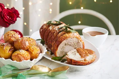 crackle pork roast with fairy lights in background and potatoes in bowl on the side